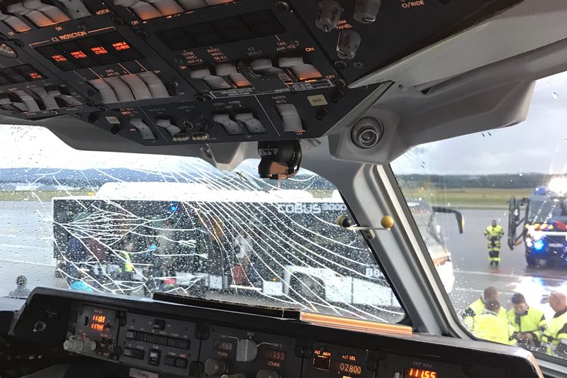 Cockpit mit gesprungener Scheibe, davor Einsatzkräfte auf dem Vorfeld